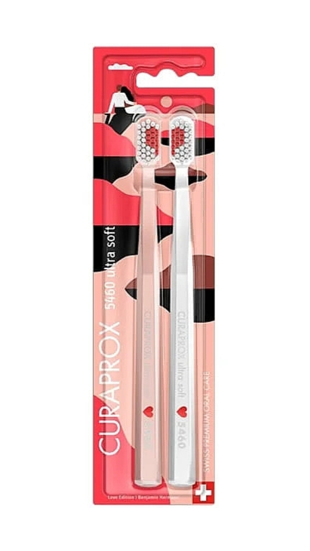 A set of two Curaprox brand toothbrushes with pink and white color scheme, packaged in a red and white cardboardslot packaging.
