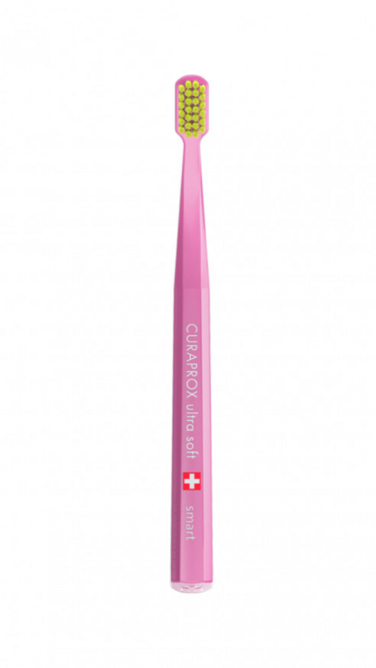 A green toothbrush designed for children, with a compact head and purple bristles, branded as 'Curaprox'.