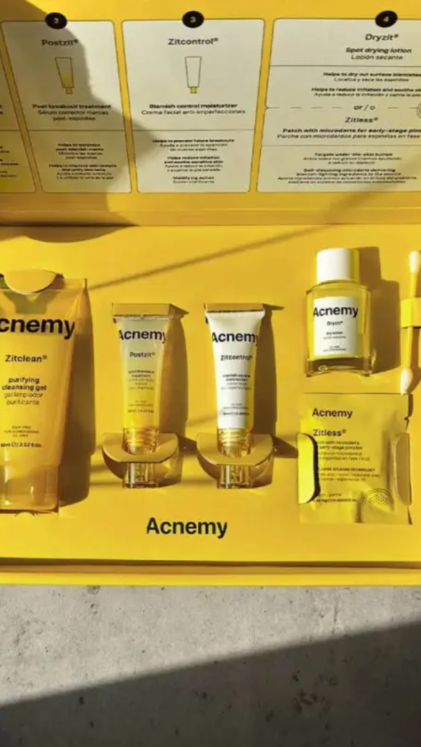 Acnemy skincare product set in a yellow box on a light gray surface.
