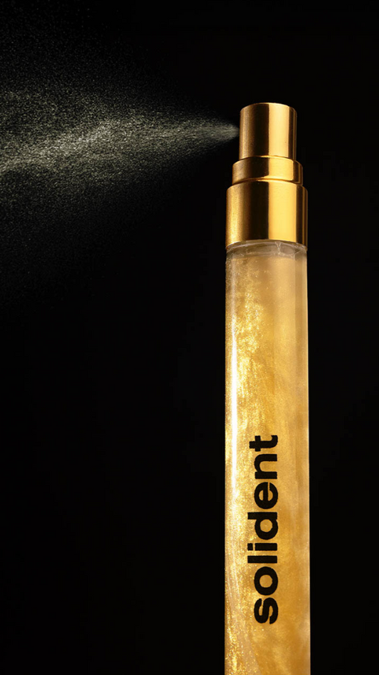 Wooden spray bottle with gold cap labeled 'solident' on a black background