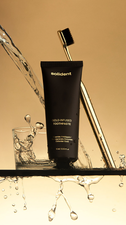Black toothpaste tube labeled 'solident' with a gold toothbrush and water splash on a beige background