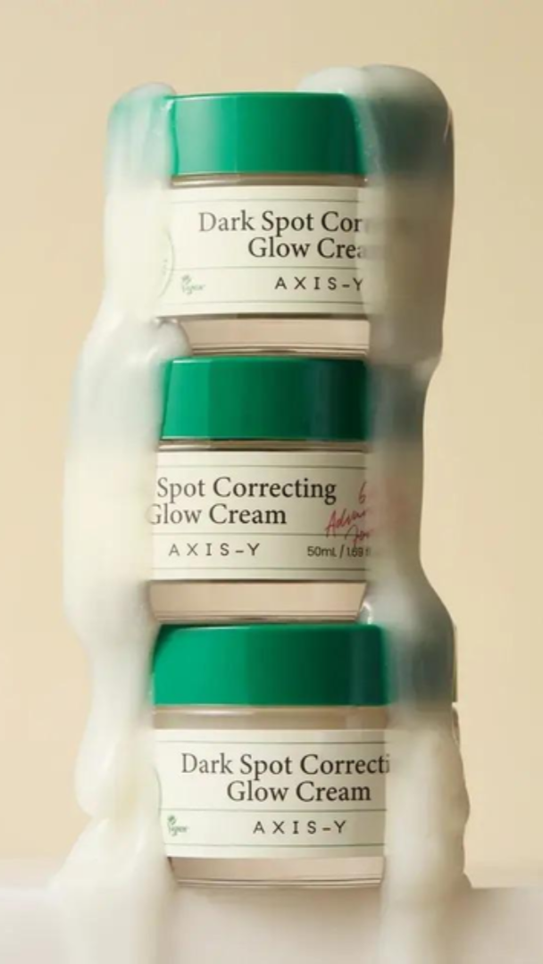 Three jars of Axis-Y Dark Spot Correcting Glow Cream on a beige background