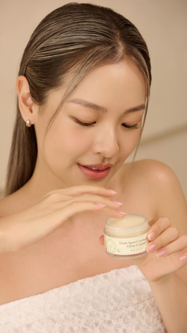 Woman holding a jar of cream with a neutral background