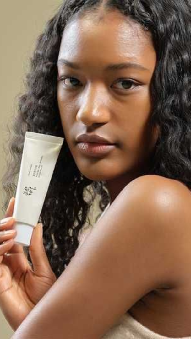 Woman holding a skincare product with a neutral background