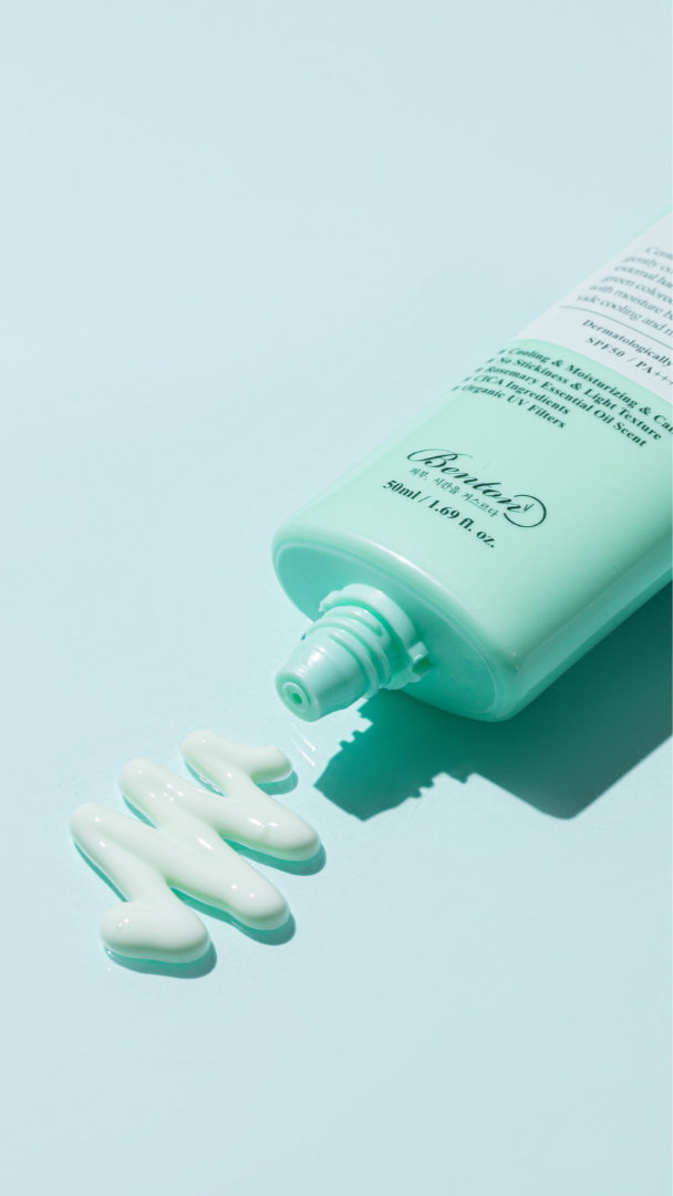Green bottle of skincare product with white cream on a light blue background