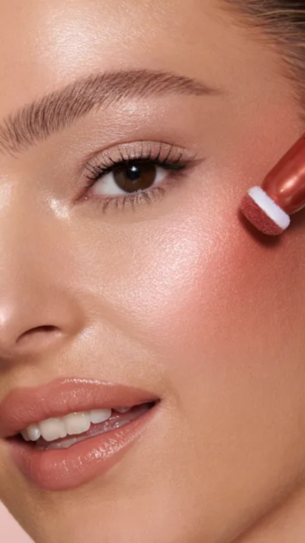 Woman applying blush with a makeup pencil on a white background