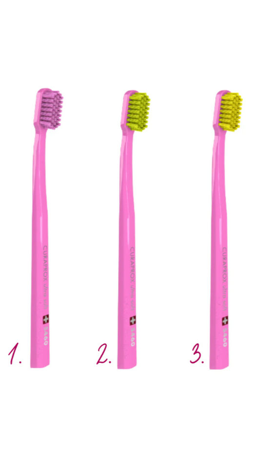 Three pink toothbrushes with different bristle colors on a white background