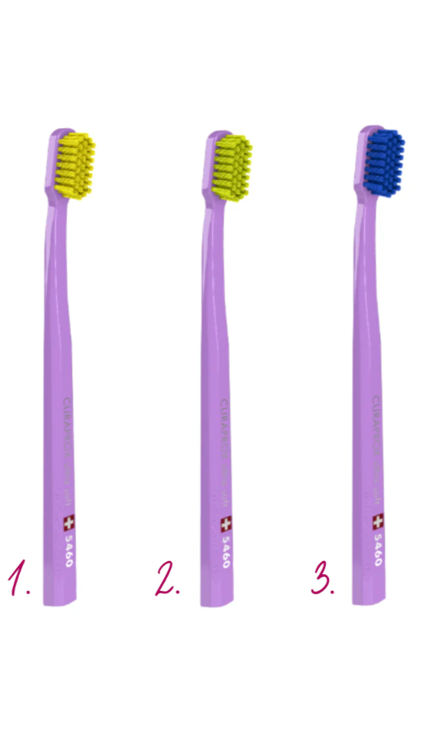 Three purple toothbrushes with colored bristles on a white background