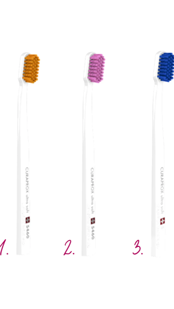 Three toothbrushes with colored bristle heads on a white background