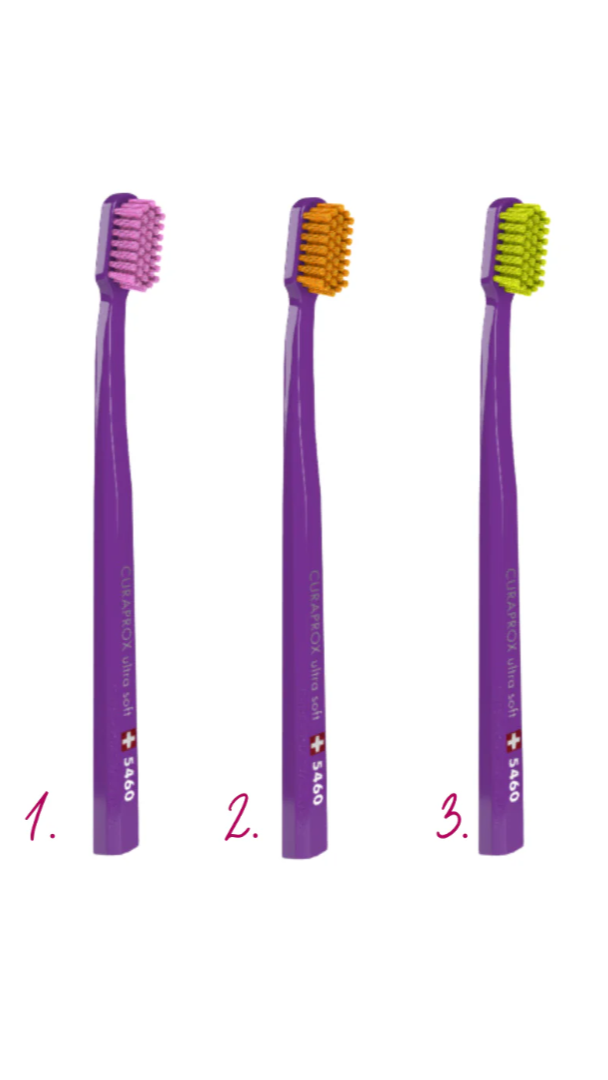 Three purple toothbrushes with different colored bristle heads on a white background