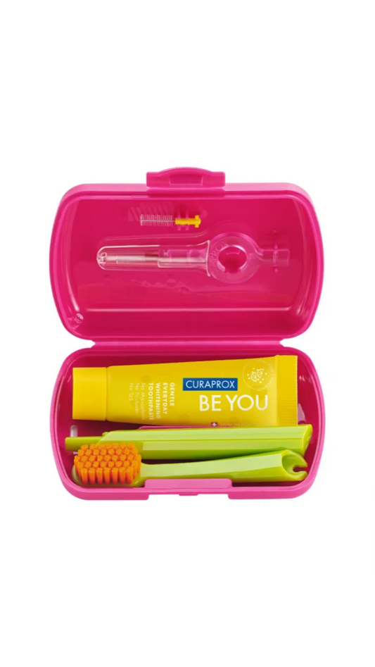Pink dental care kit with toothbrush, toothpaste, and floss on a white background