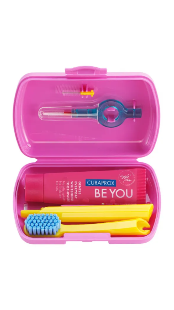 Pink dental care kit with toothbrush, toothpaste, and tools on a white background