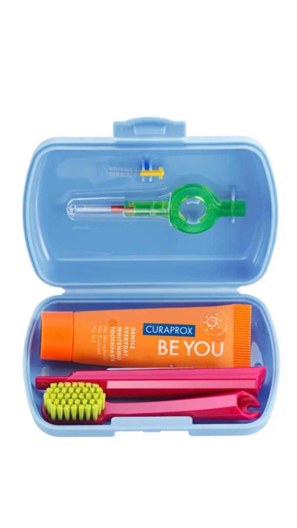 Oral care kit with toothbrush, toothpaste, and other items in a blue case on a white background