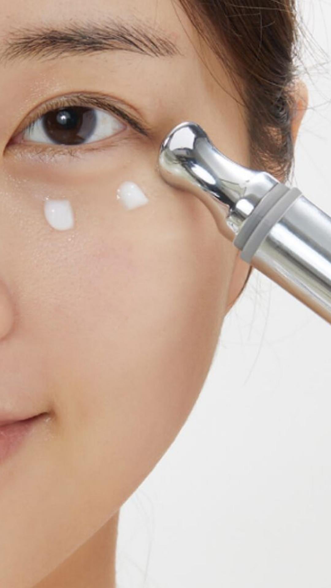 Close-up of a person using a skincare tool on their face with a white background