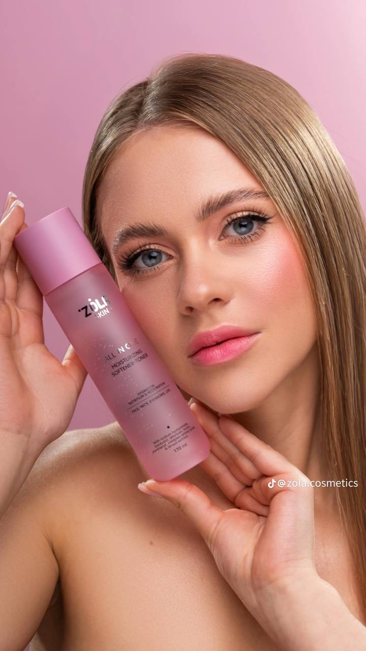 Woman holding a pink bottle with 'ZUI' branding against a pink background